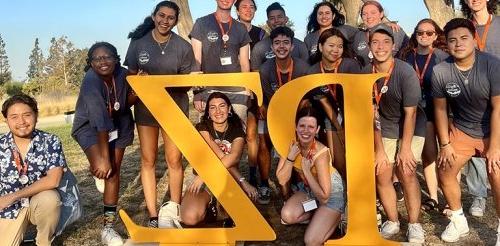 A group of students standing in behind oversized letters spelling "P" and "Z".